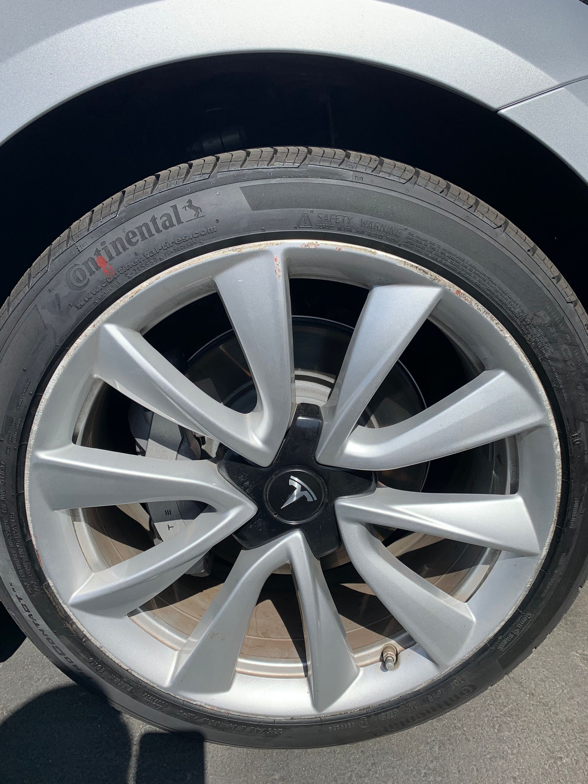 Close-up of a silver car wheel with a black tire and multi-spoke rim.