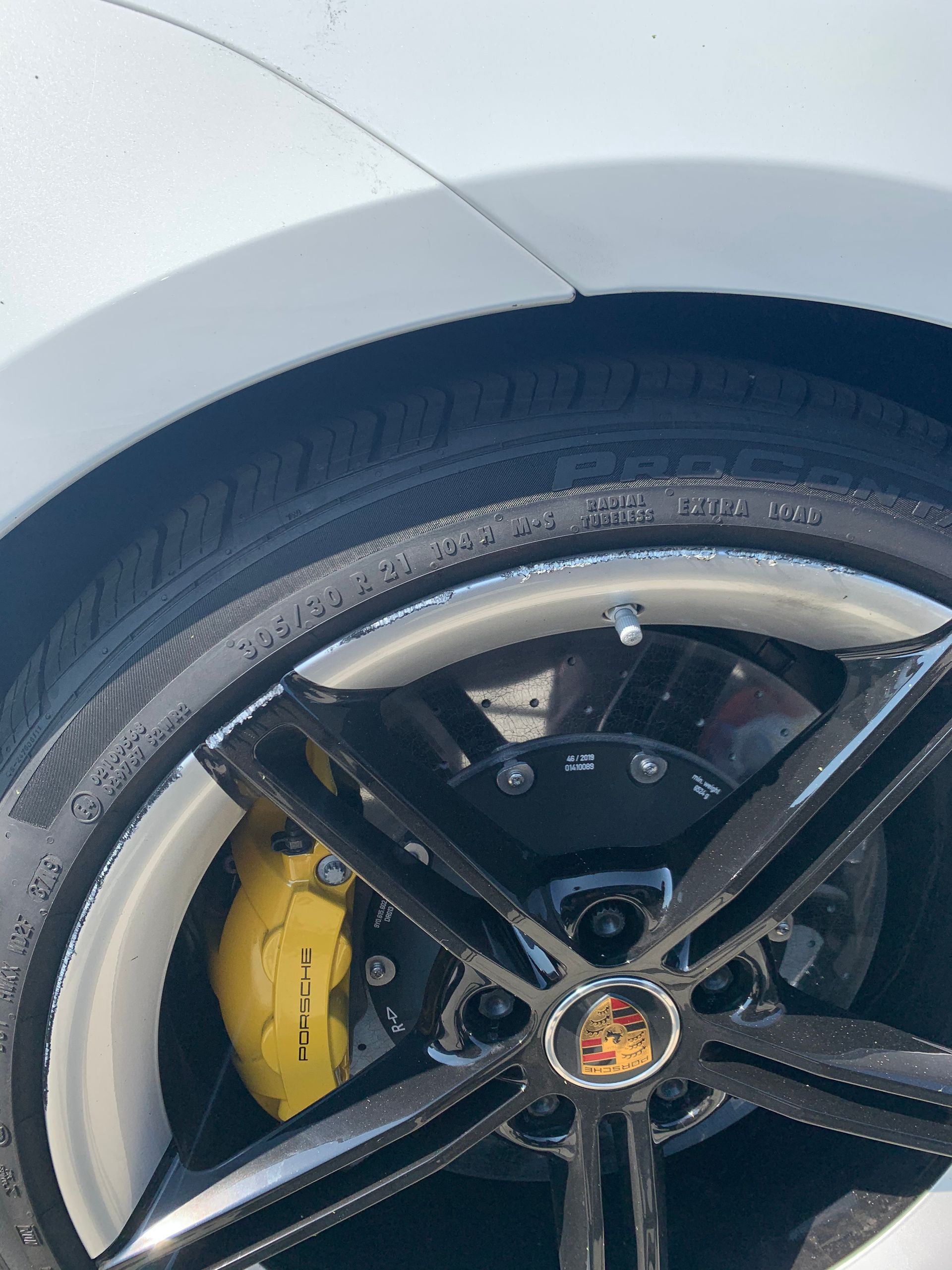Close-up of a sports car wheel with black rim and yellow brake caliper.