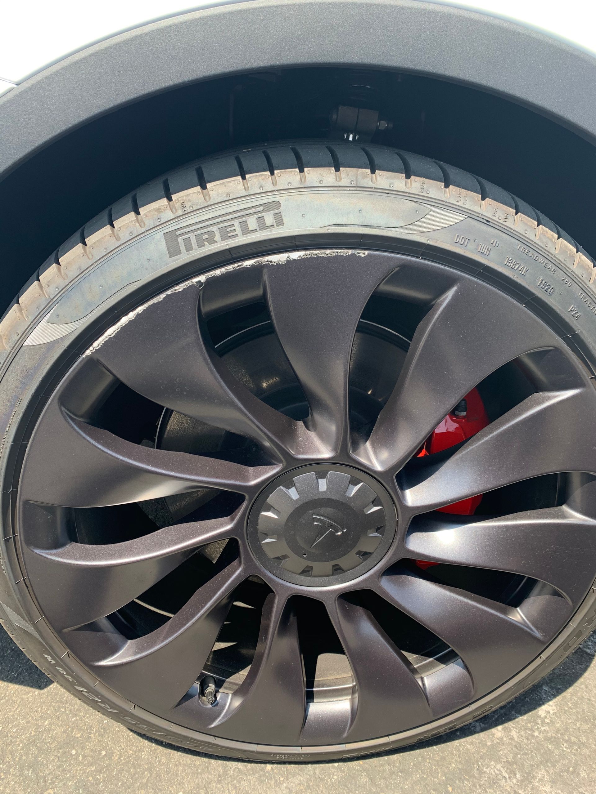 Close-up of a car wheel with a black custom rim and visible red brake caliper.