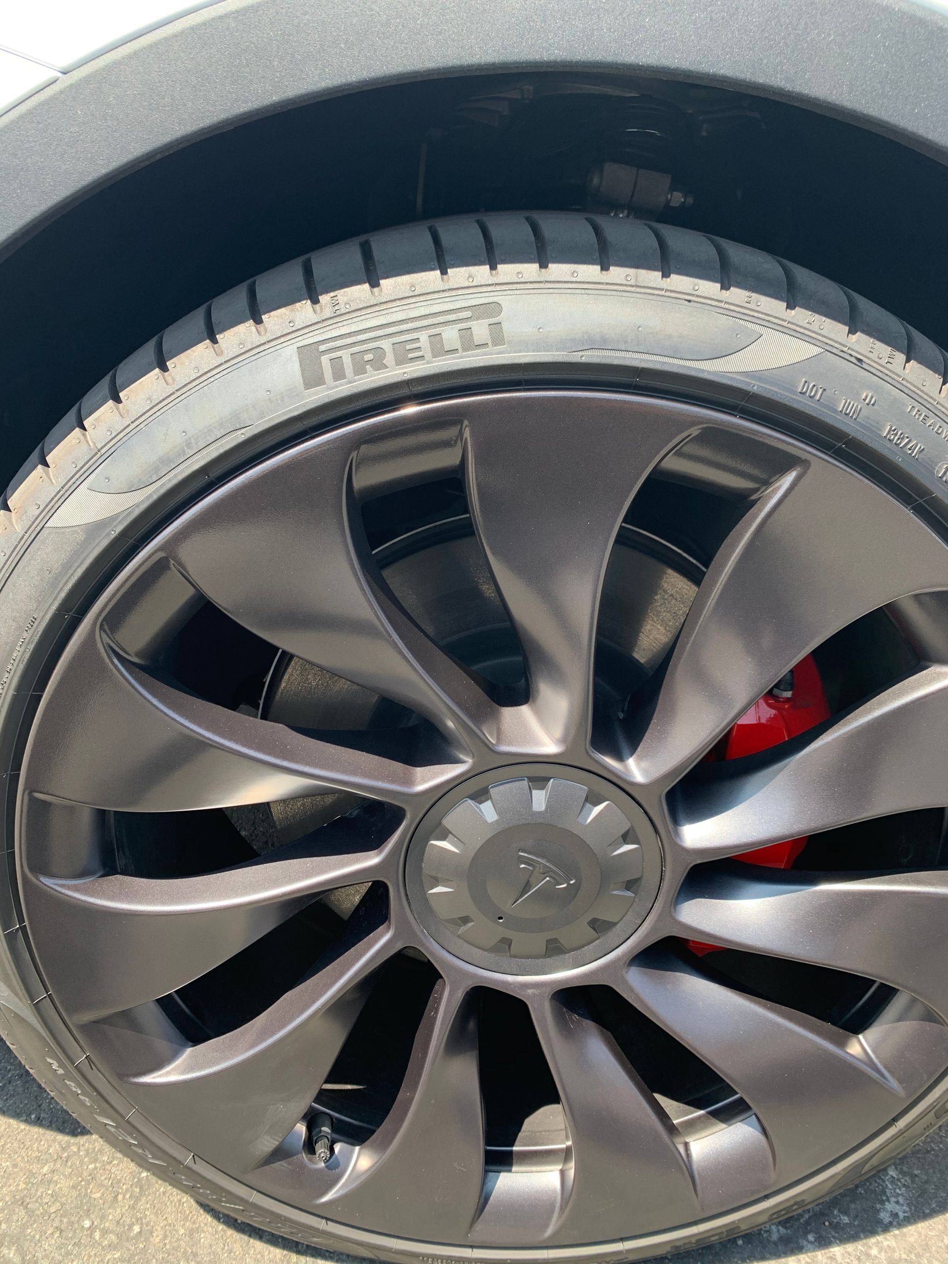 Close-up of a car wheel with black alloy rim and red brake caliper.