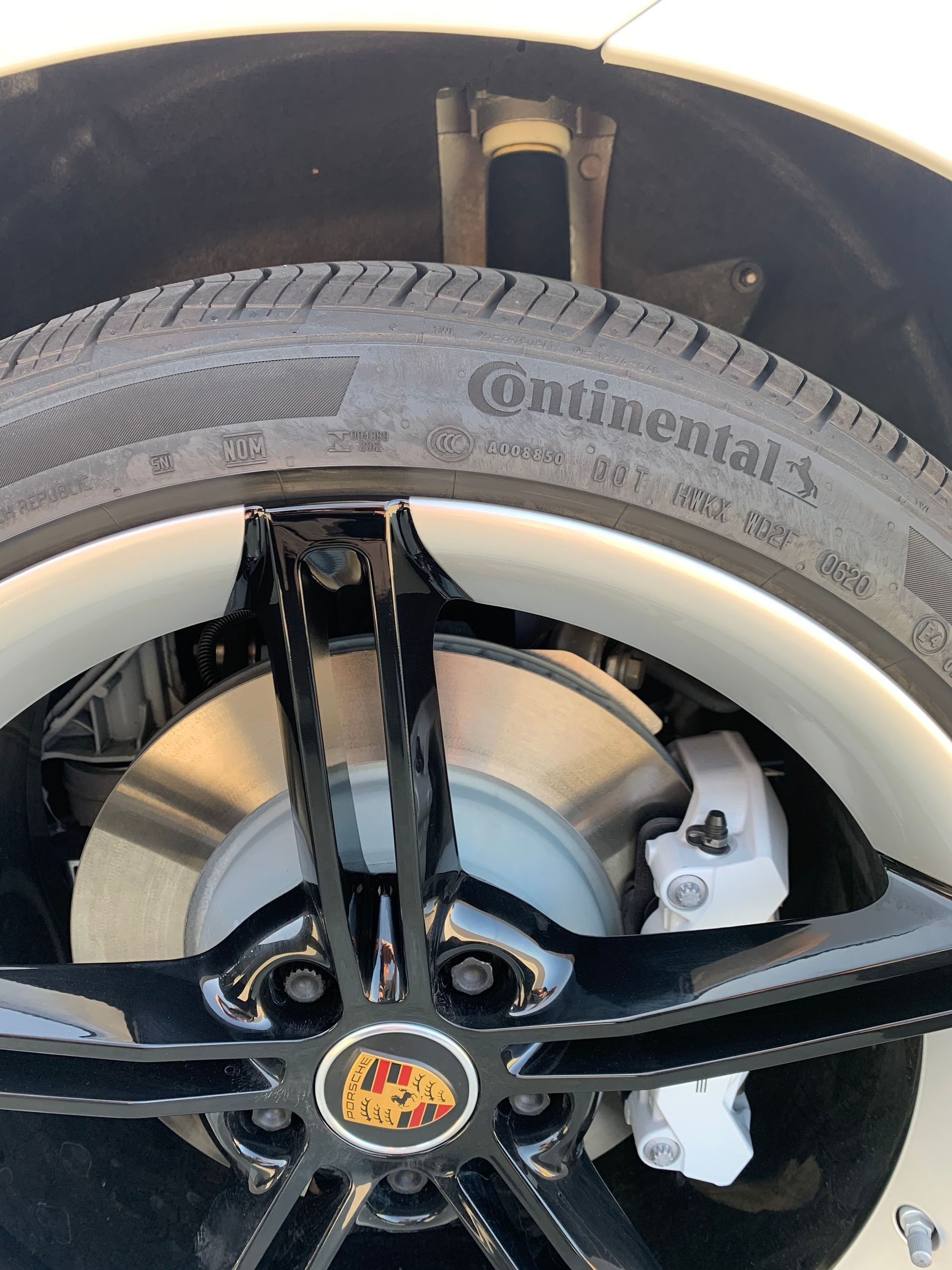 Close-up of a car wheel with black spokes, white rim, and Continental tire tread.