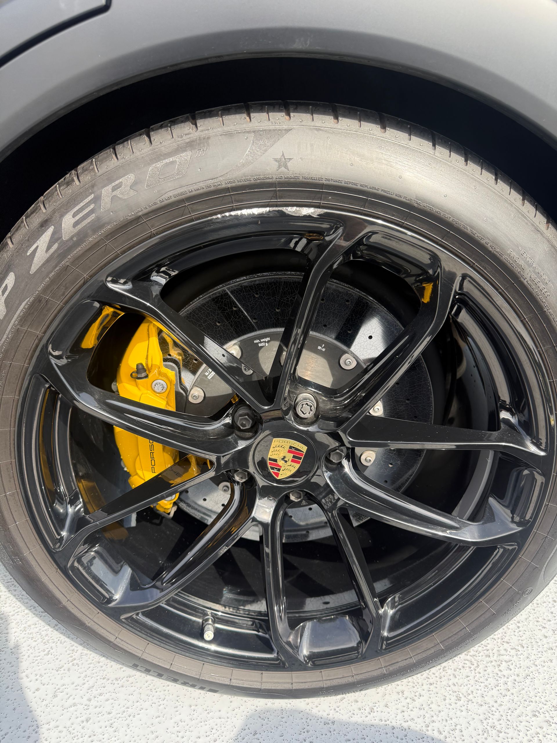 Close-up of a black alloy car wheel with a yellow brake caliper and worn tire tread.