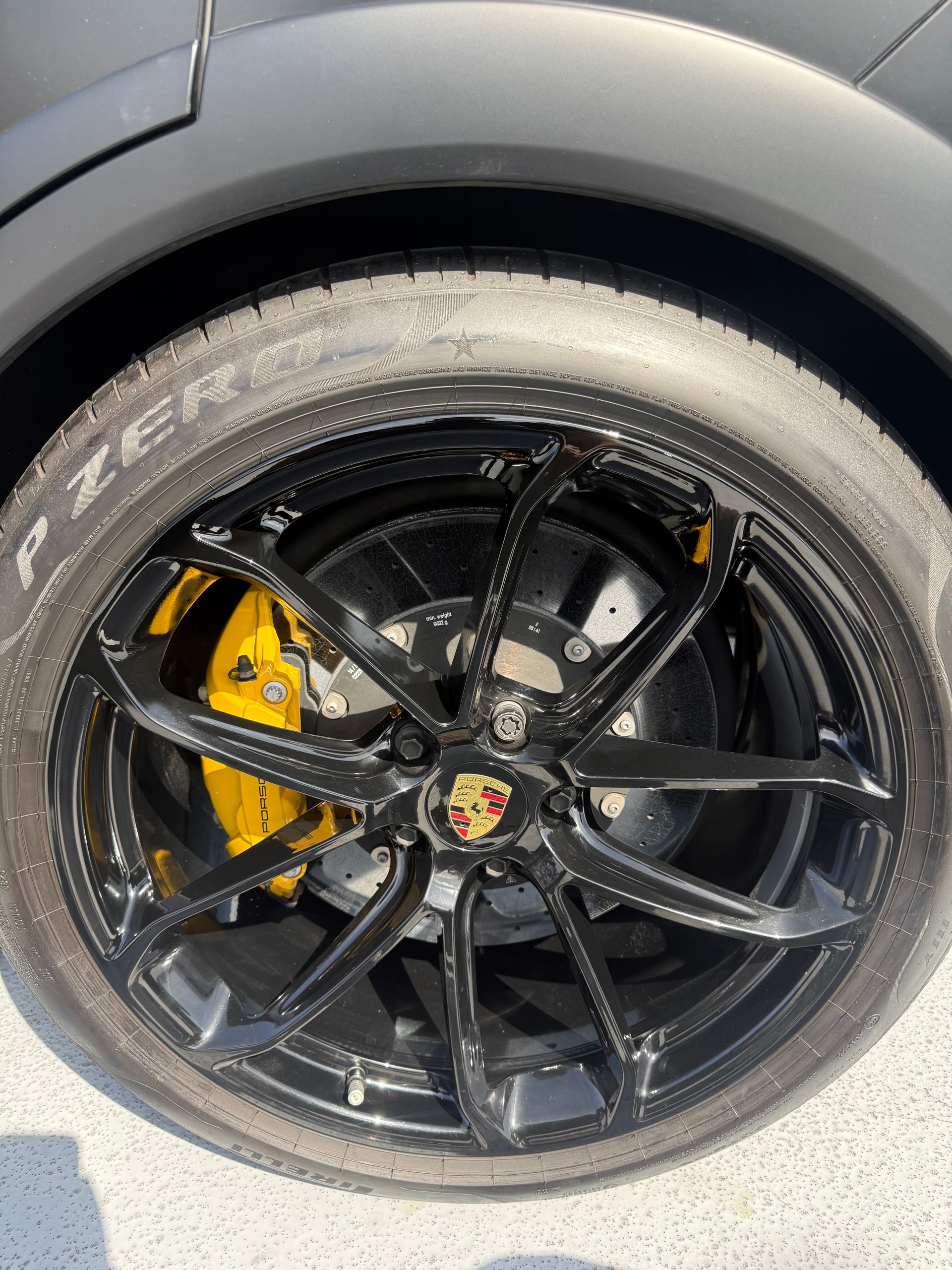 Close-up of a black sports car wheel with yellow brake caliper and silver tire sidewall text.