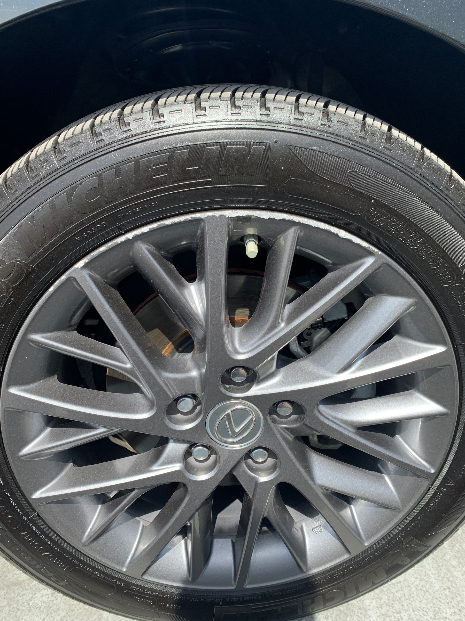 Close-up of a silver alloy car wheel and tire with a Toyota logo hubcap.