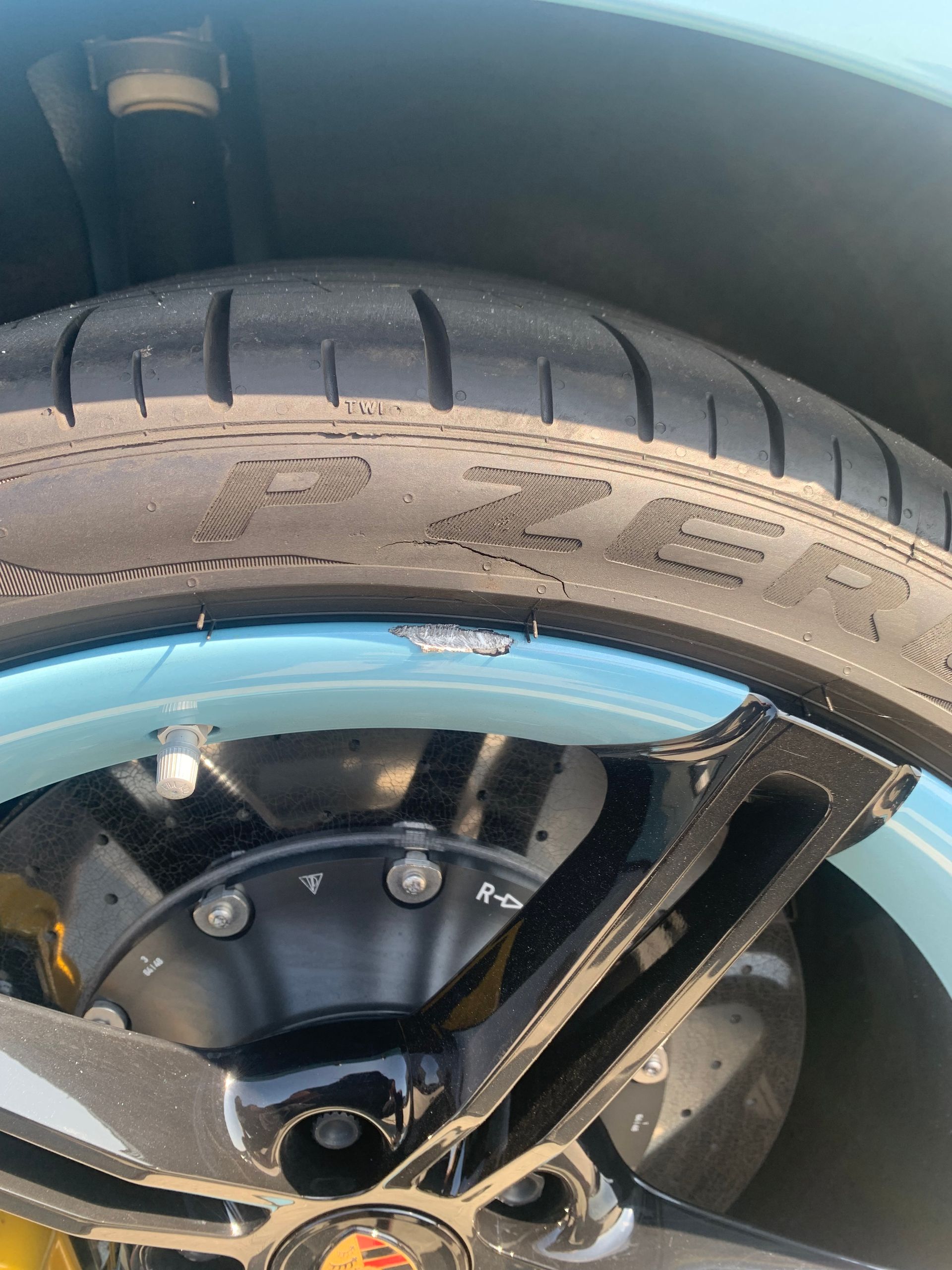 Close-up of a black tire and wheel with blue rim trim on a vehicle.