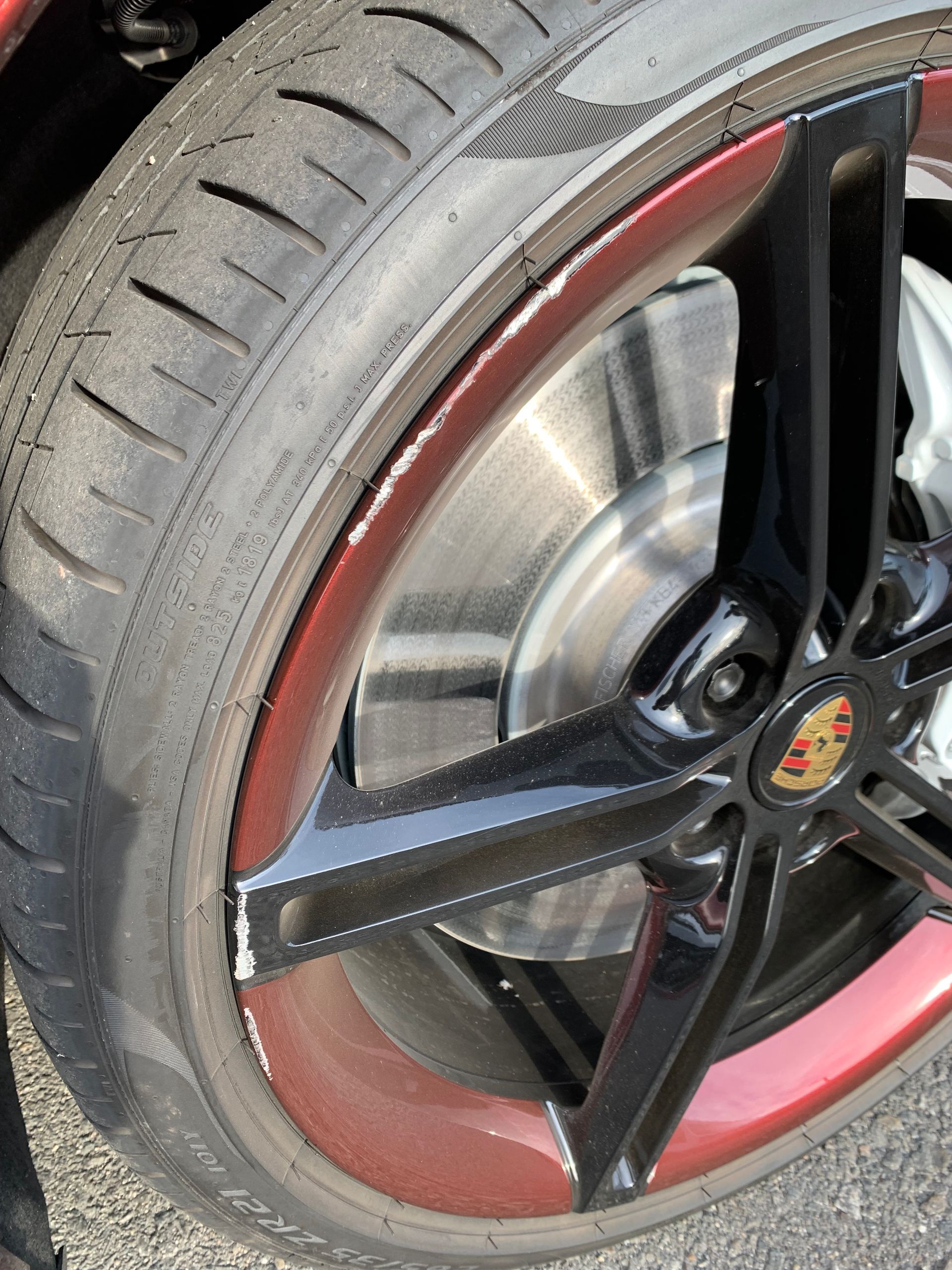 Close-up of a car wheel with black spokes, red rim accents, and visible tire tread.