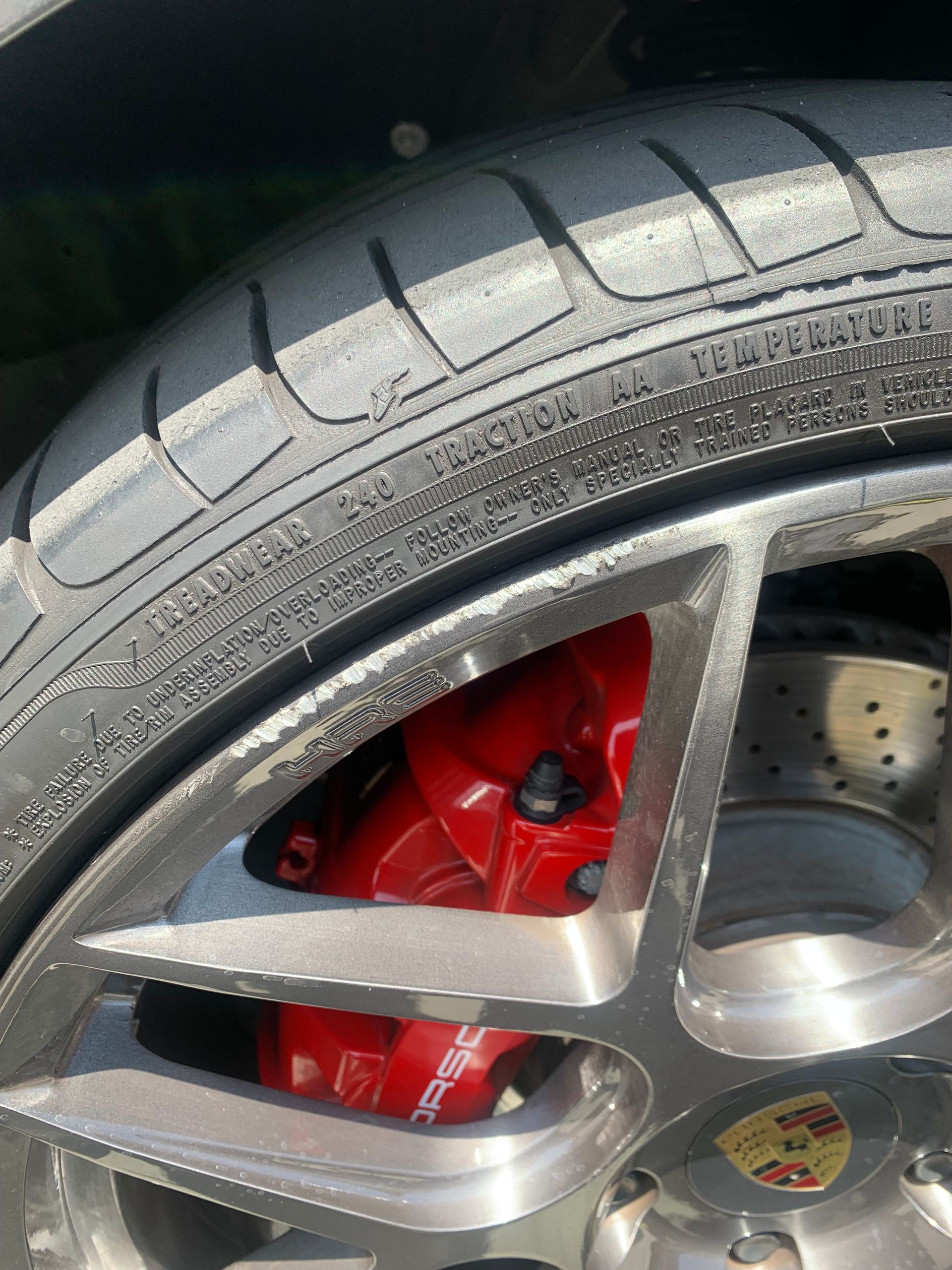 Close-up of a car wheel with silver rim, black tire, red brake caliper, and ventilated brake rotor.