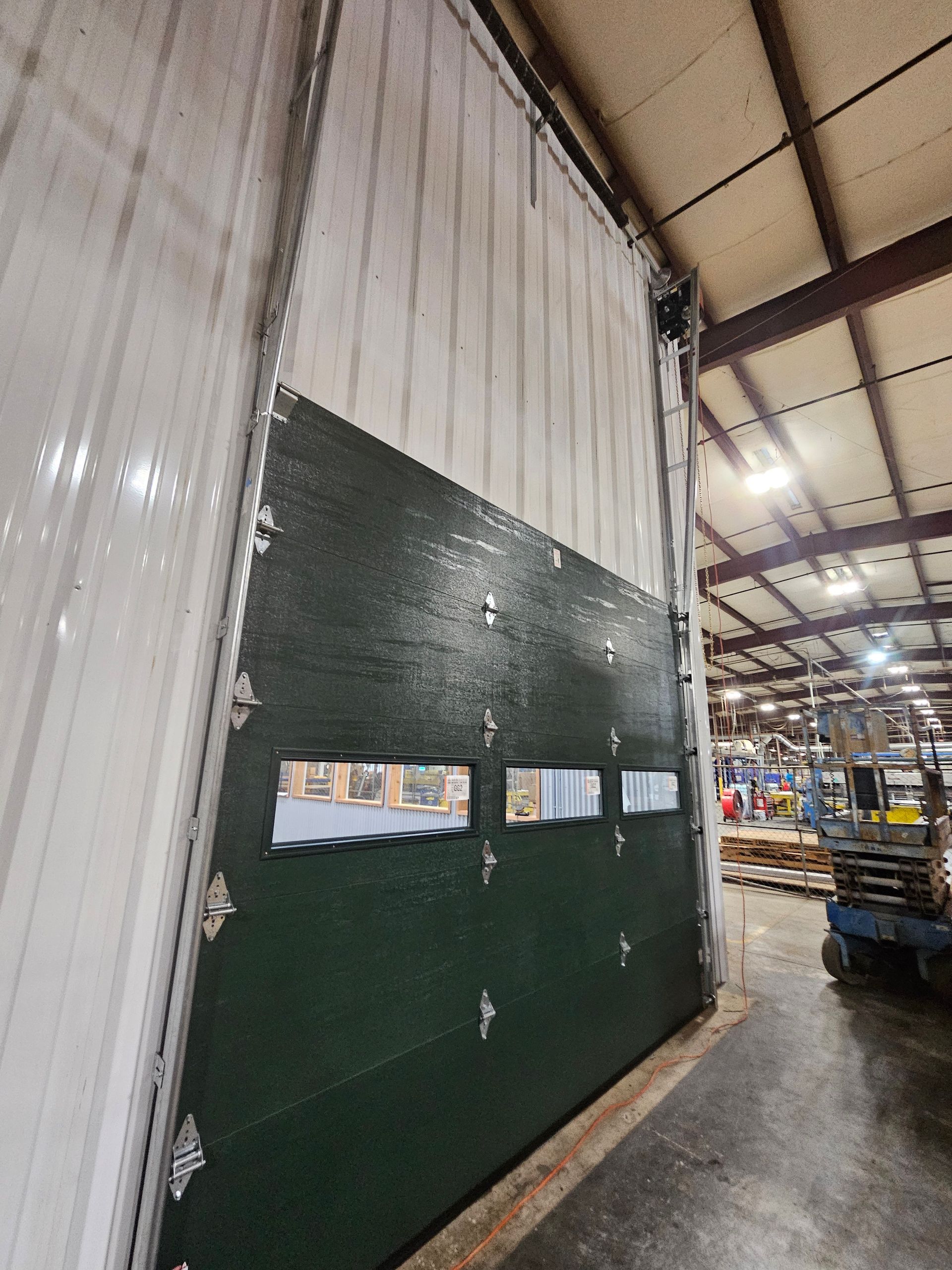 A large green garage door is open in a warehouse.