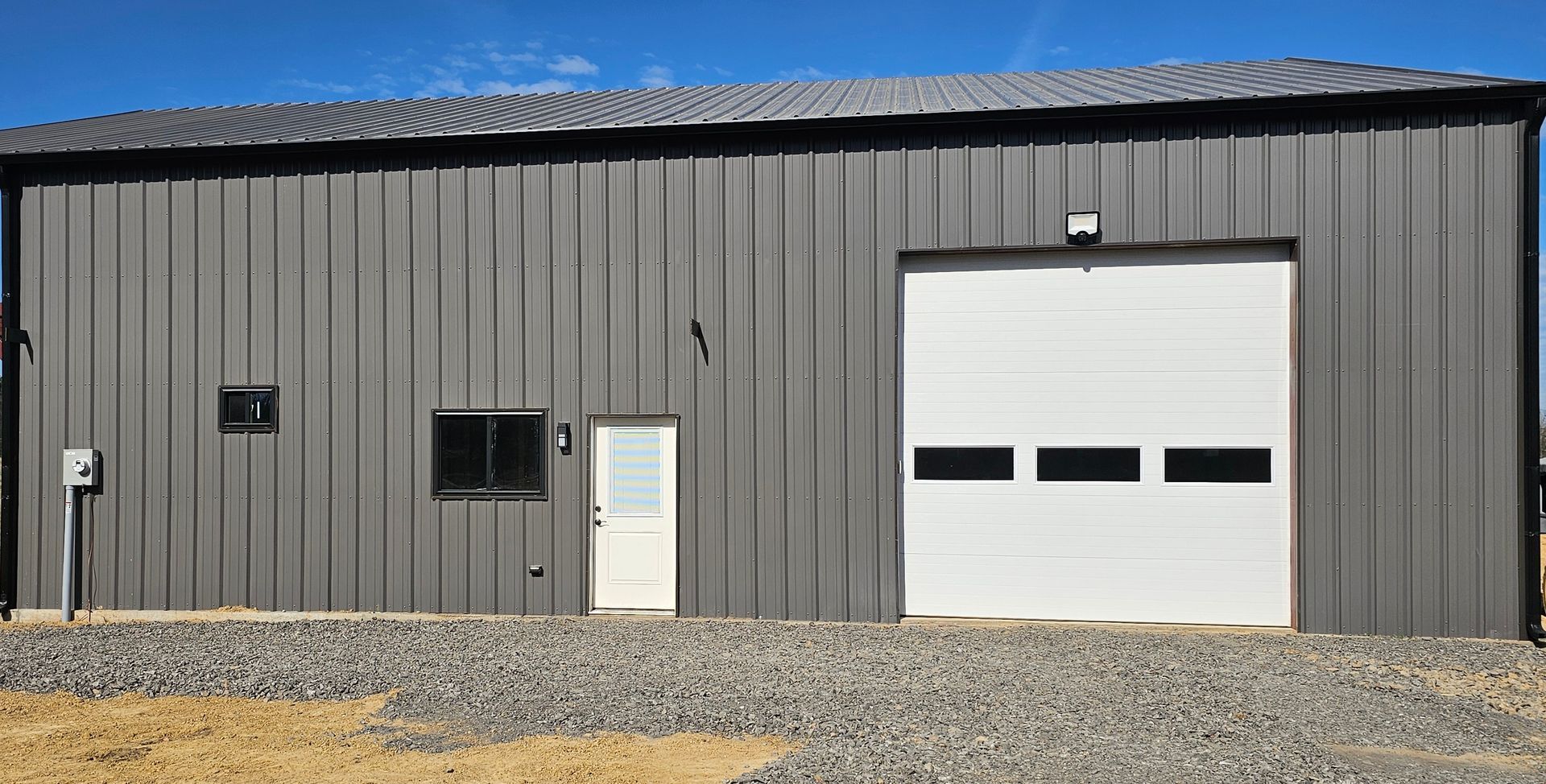 A large gray metal building with a white garage door.