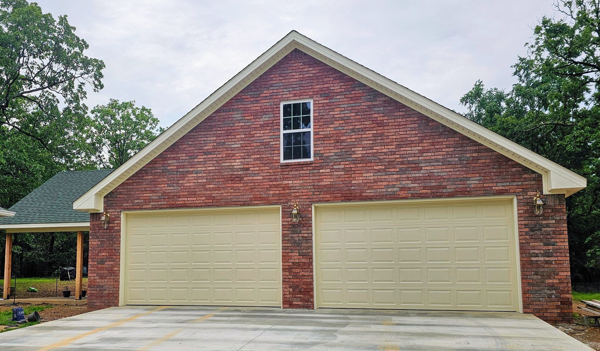 A brick garage with two white garage doors and a window