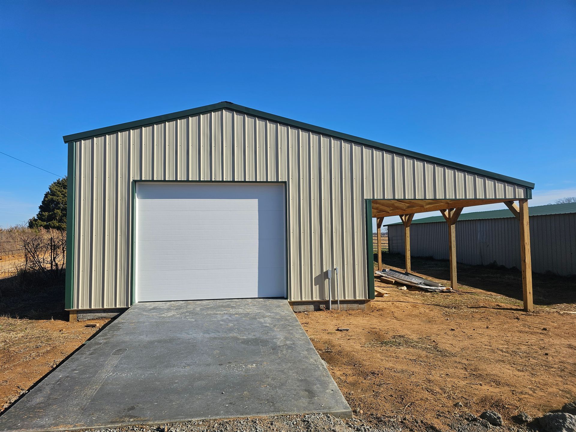 A metal building with a garage door and a carport