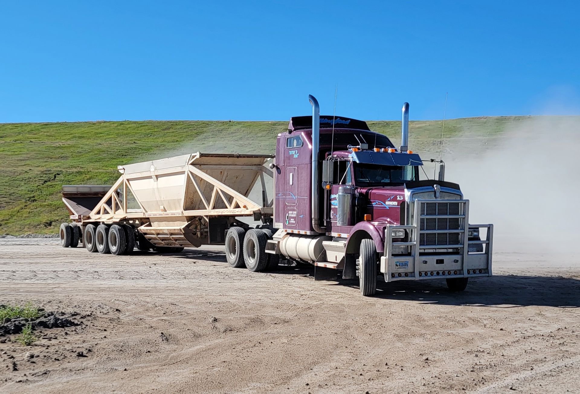 a red semi truck is driving down a dirt road
