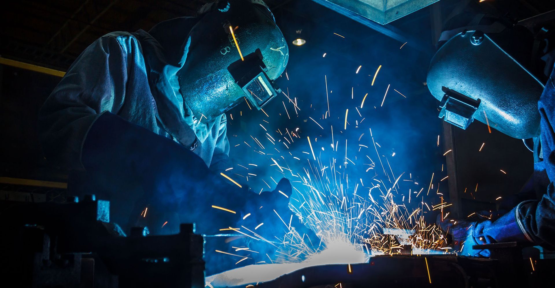 a man is welding a piece of metal in a factory