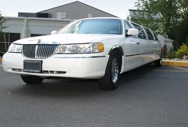 White limousine parked in a parking lot, daytime.