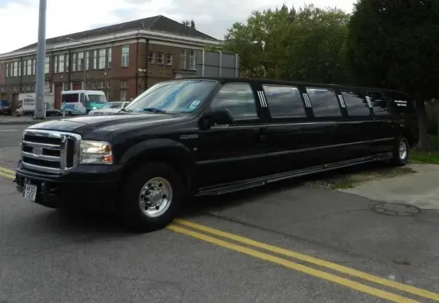 Black limousine parked on a street with a building in the background.