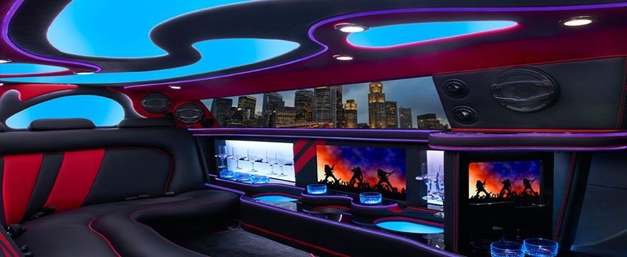 Interior of a luxurious limousine with a blue and red color scheme and city view.