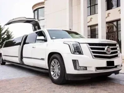 White Cadillac limousine with open doors parked in front of a building.