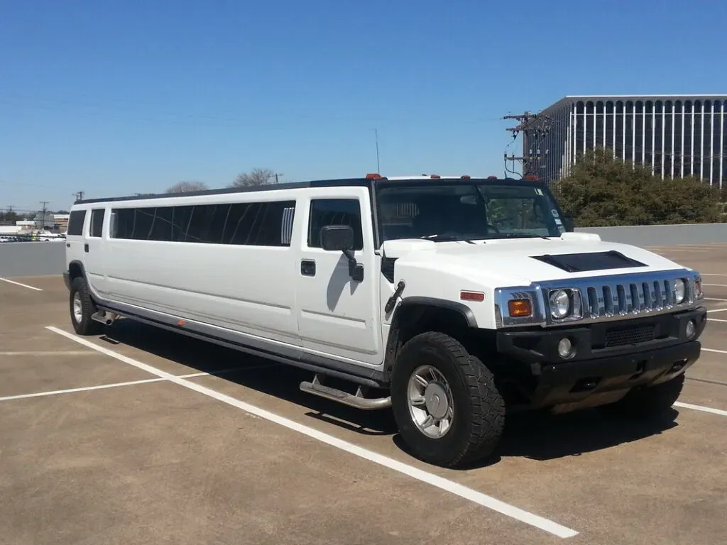 White Hummer limousine parked in an outdoor lot on a sunny day.