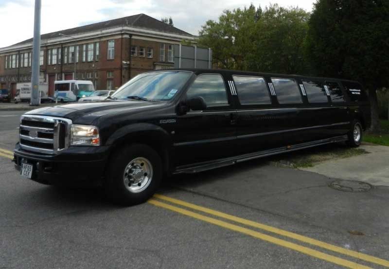 Black limousine parked on a street with a building in the background.