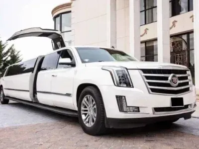 White Cadillac limousine with open doors parked in front of a building.