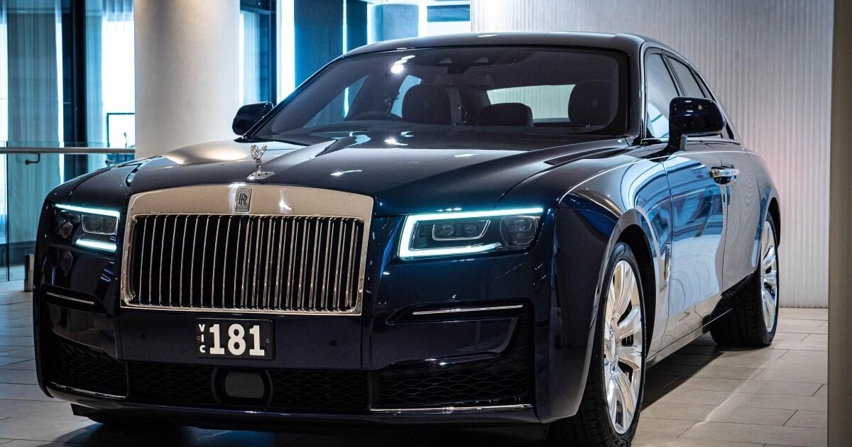 Dark blue Rolls-Royce sedan parked indoors with a silver grille and headlamps.