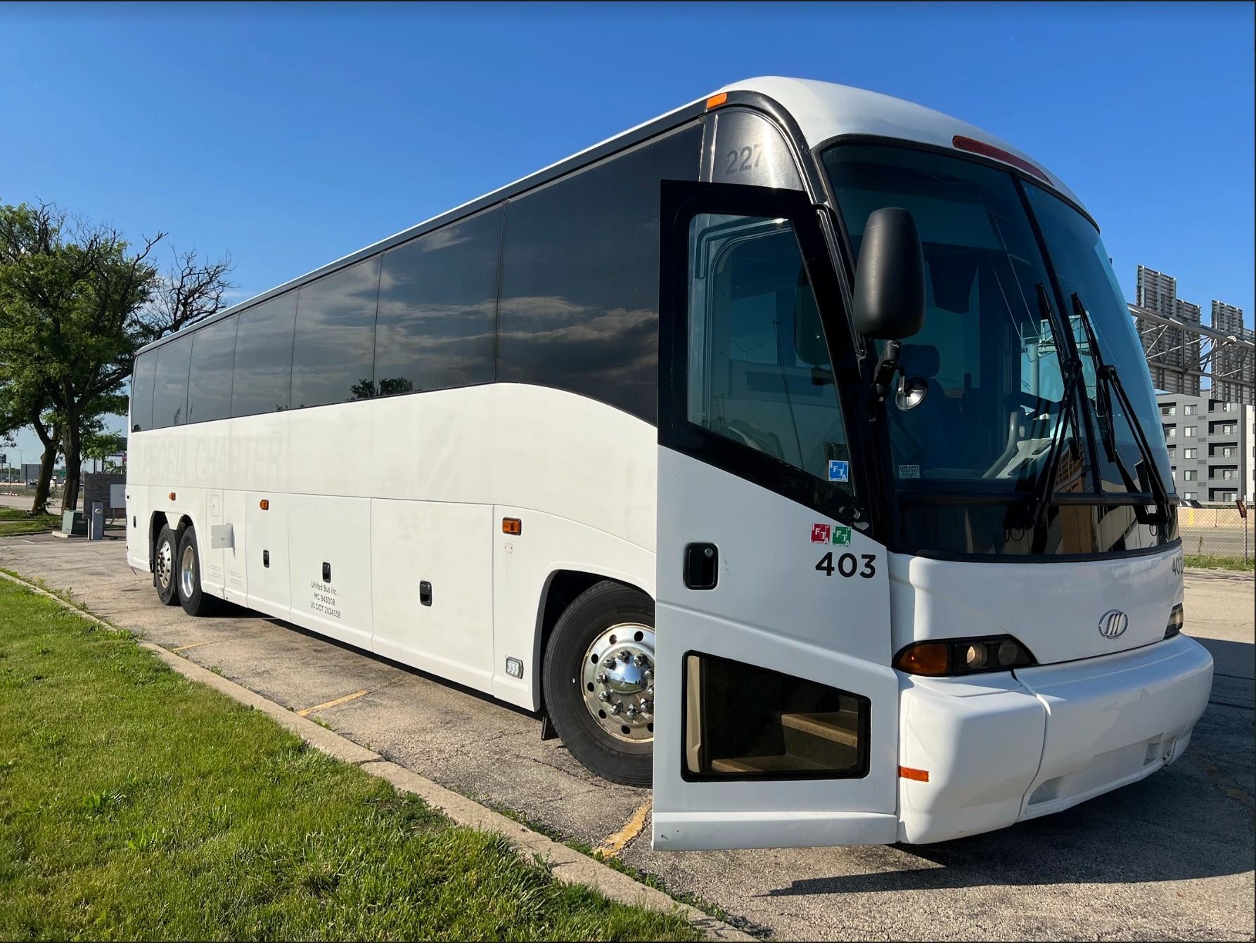 White passenger bus with open door parked on a street.