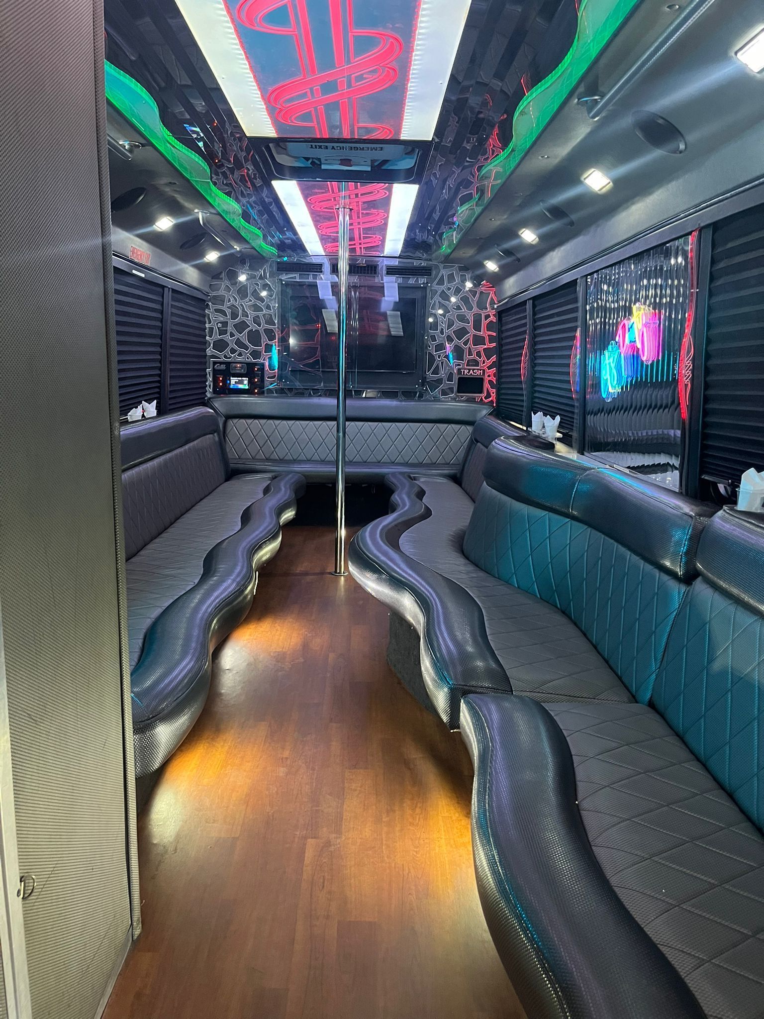 Interior of a party bus with mirrored ceiling, seating along the sides, and a dance pole in the center.