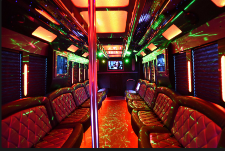Interior of a party bus: red and black leather seating, dance pole, neon lights, and a small screen.