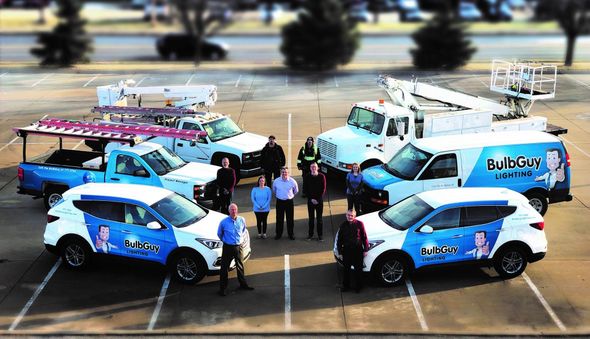 Team and vehicles of "Big Dog" company in parking lot. Trucks and SUVs; blue, white, and pink.