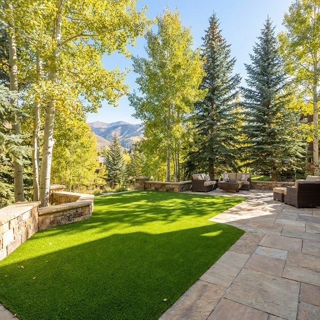 Curved white walkway through a bright green landscaped garden with trimmed hedges and young trees