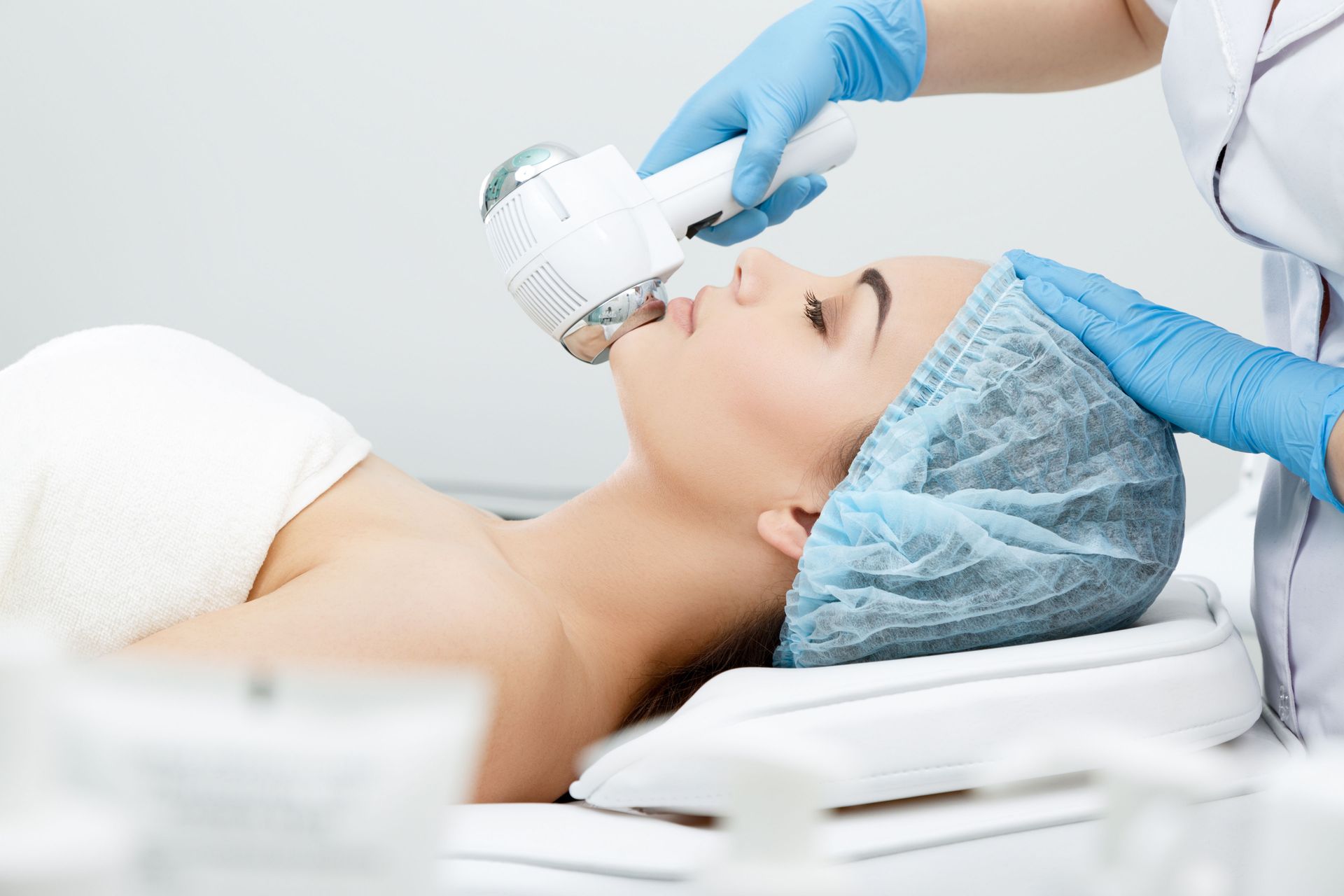 Woman receiving a facial treatment with a handheld device in a clinical setting.