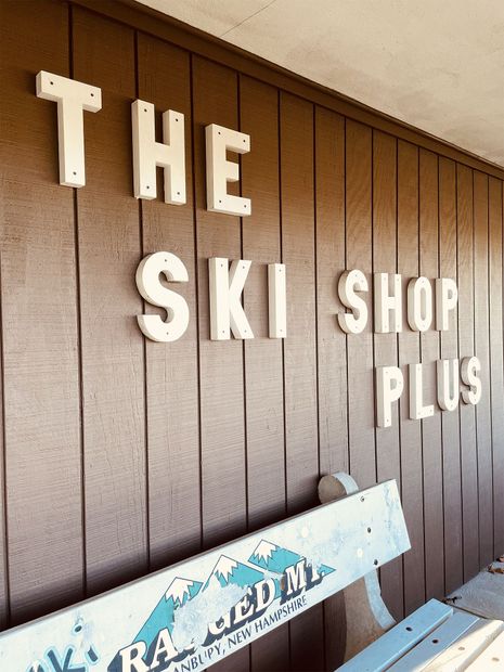 A sign on a wooden wall that says the ski shop plus