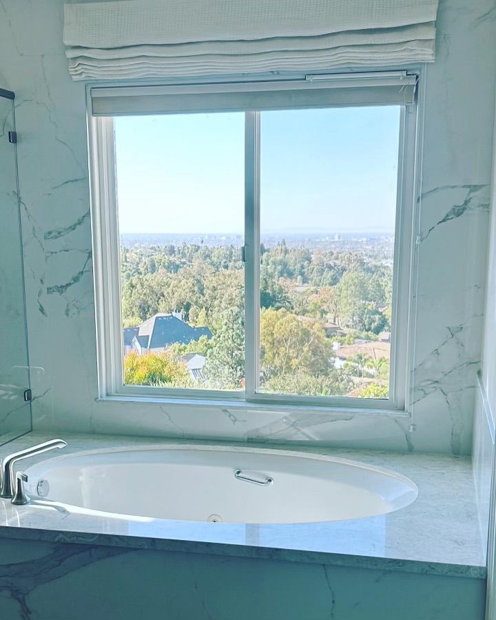 A bathroom with a tub and a window with a view of a city.