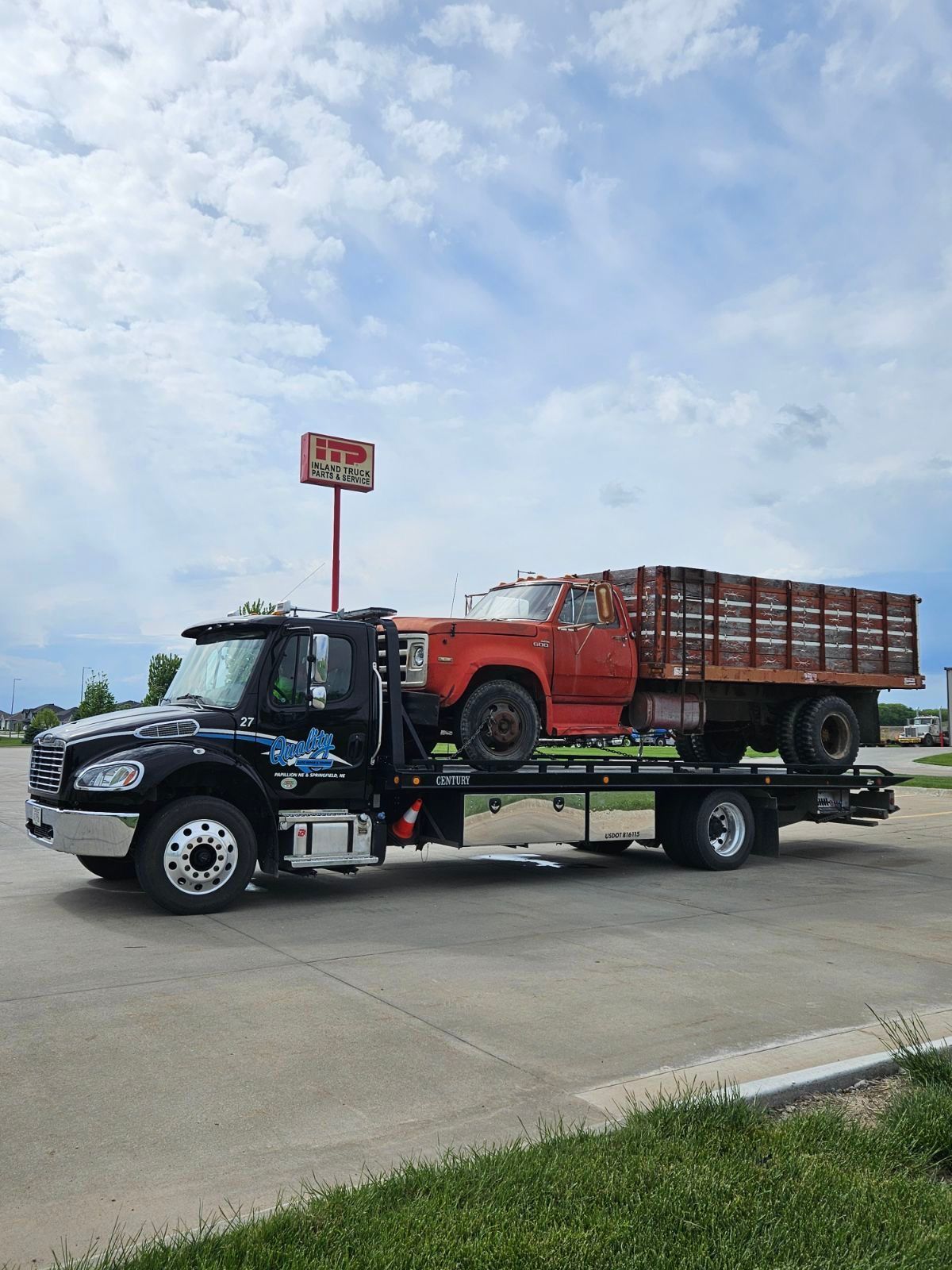 A tow truck is carrying a truck and a pickup truck.