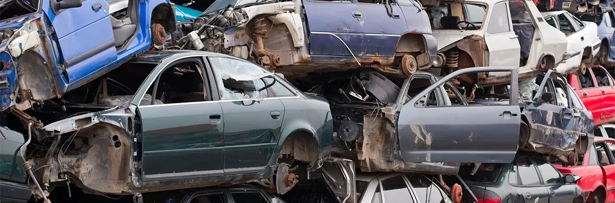A scrap yard filled with crushed cars of various colors and models.