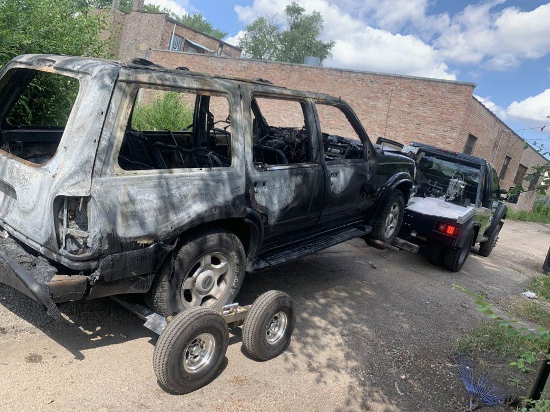 Burnt SUV being towed away by a tow truck.