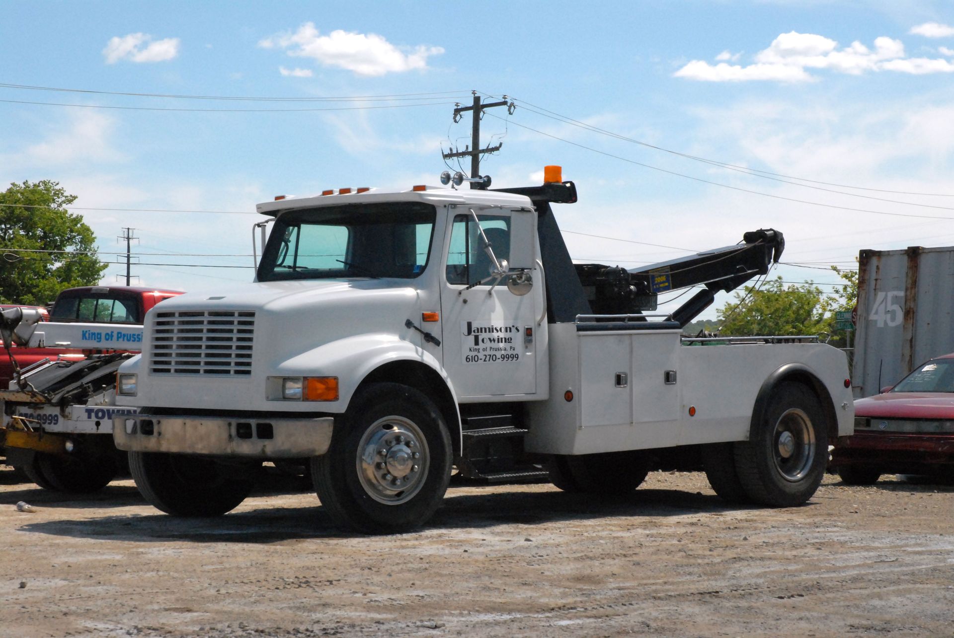 White tow truck parked outdoors on a sunny day.