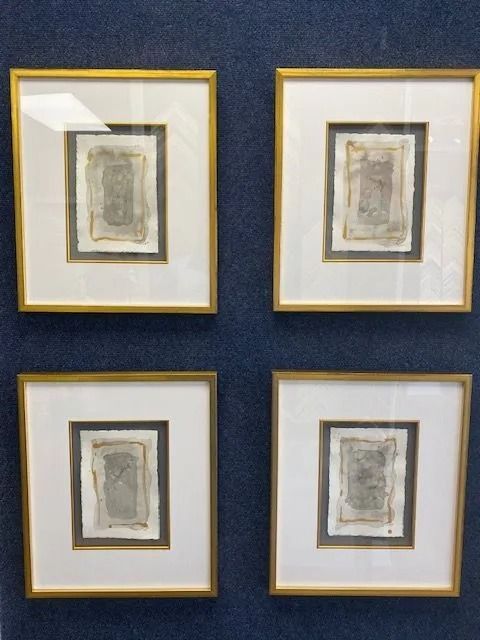 Four framed artworks, each with a gold frame, white mat, and a gray-toned rectangular image.