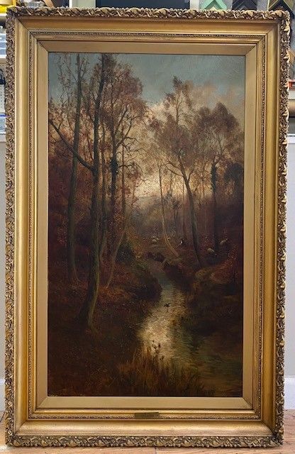 Oil painting of a stream winding through a wooded landscape. Autumnal tones, with bare trees and a golden-framed border.