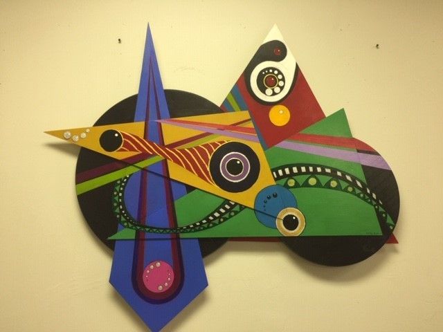 Abstract wooden artwork with geometric shapes in various colors mounted on a wall.
