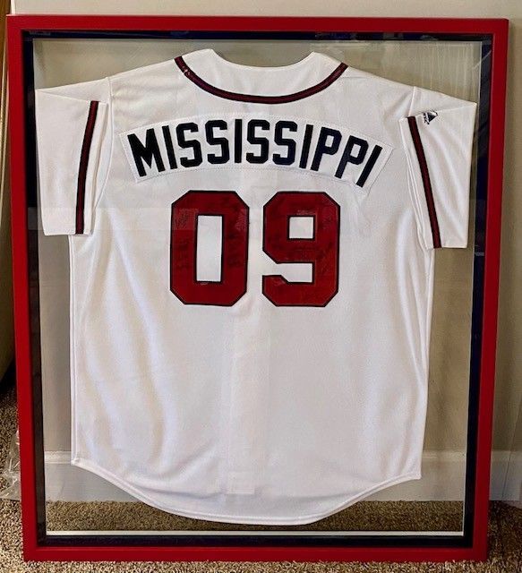 A white baseball jersey framed in red. The back displays 