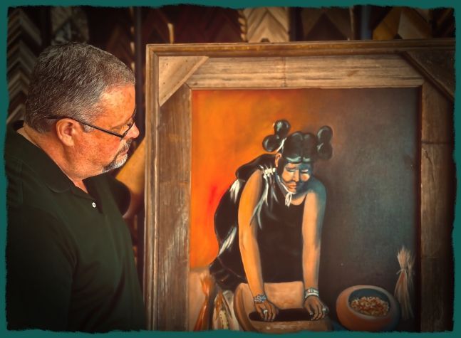 A man with glasses examines a framed painting depicting an Indigenous figure in a black dress.