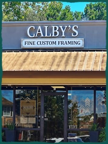 Exterior of Calby's Fine Custom Framing store with a sign and a glass door entrance under an awning.