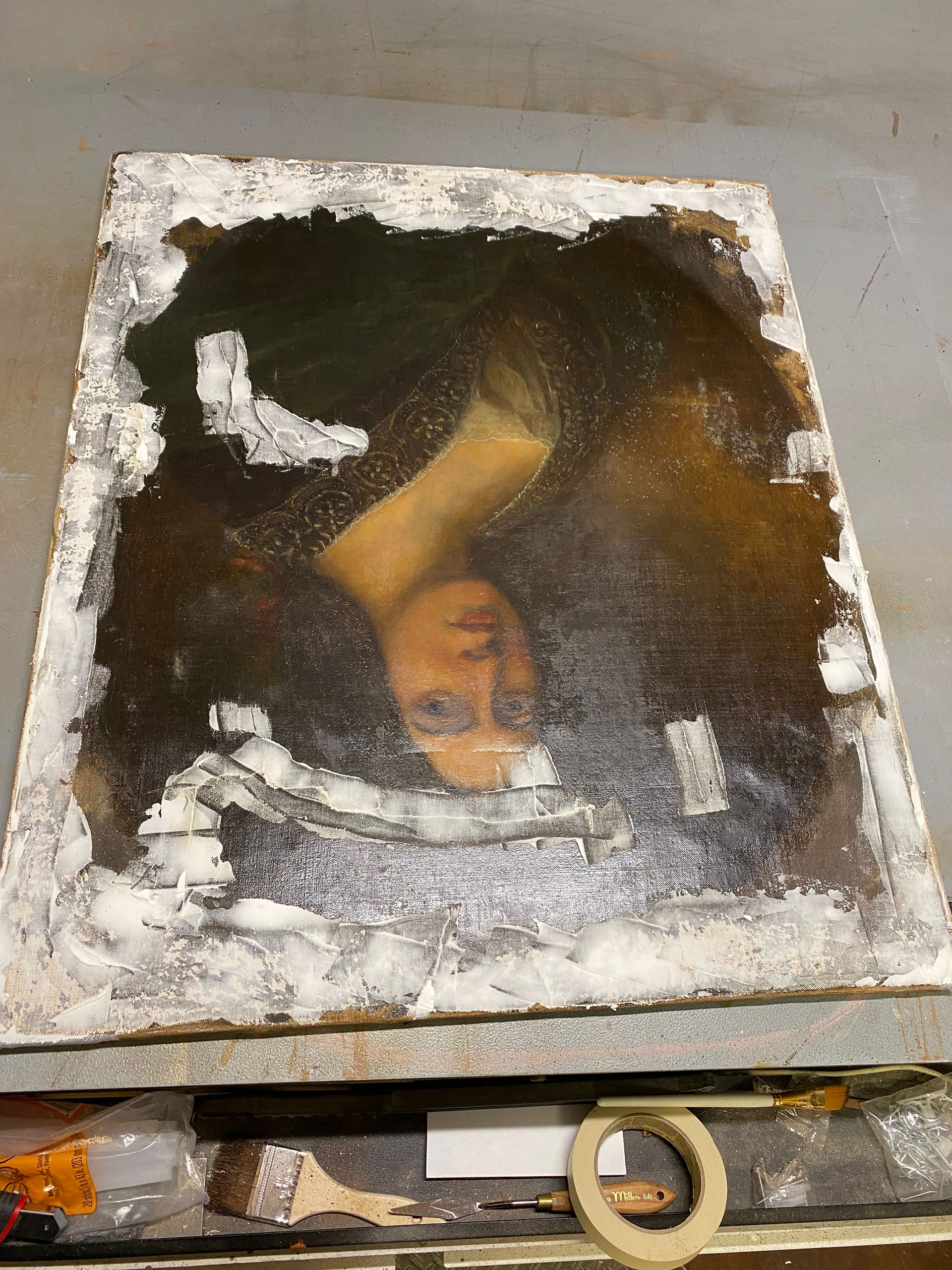 A deteriorating portrait of a woman with visible cracking and damage, surrounded by a white, flaking frame.