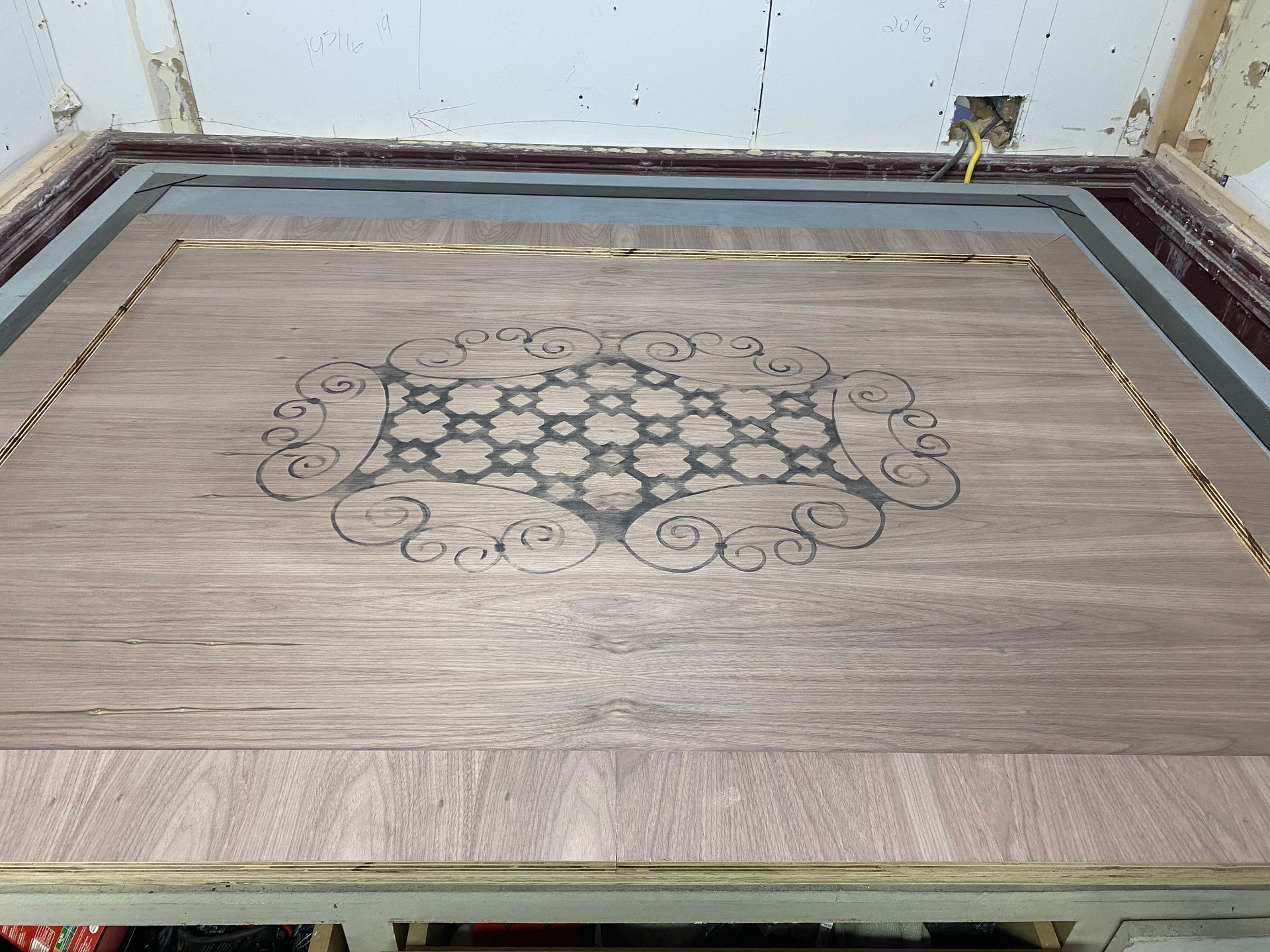 A wooden inlay with a floral pattern is centered in a rectangular frame, likely for a door or table.