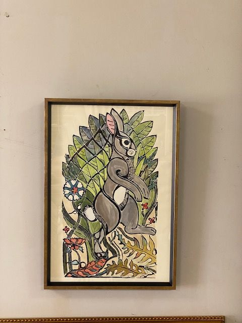 Framed artwork featuring a grey rabbit surrounded by green foliage and flowers.