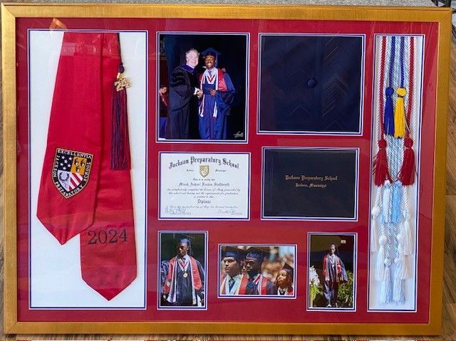 Framed graduation mementos: red and white stoles, photos of graduate in cap and gown, diploma, and tassel.