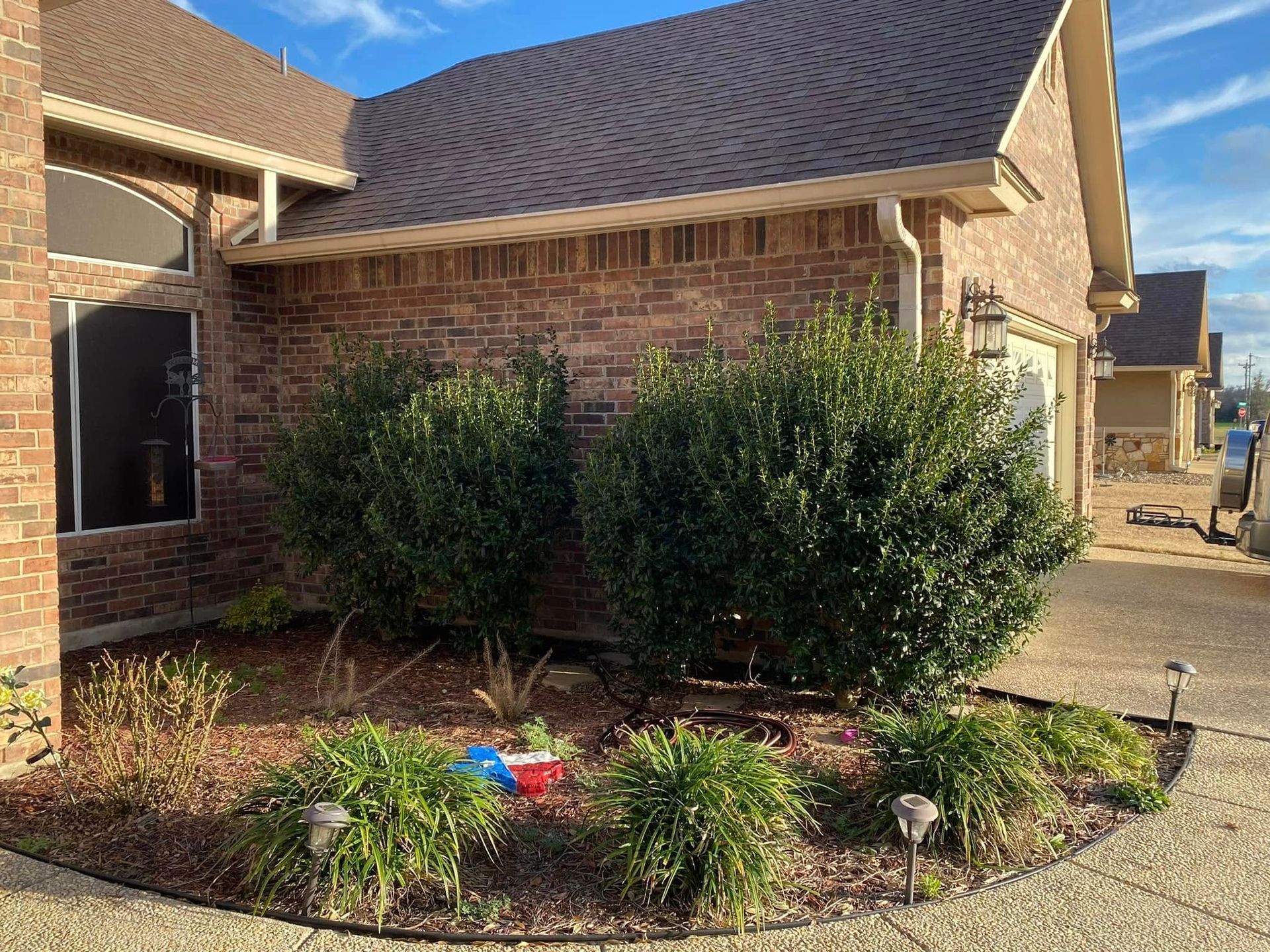 A brick house with a lot of bushes in front of it.