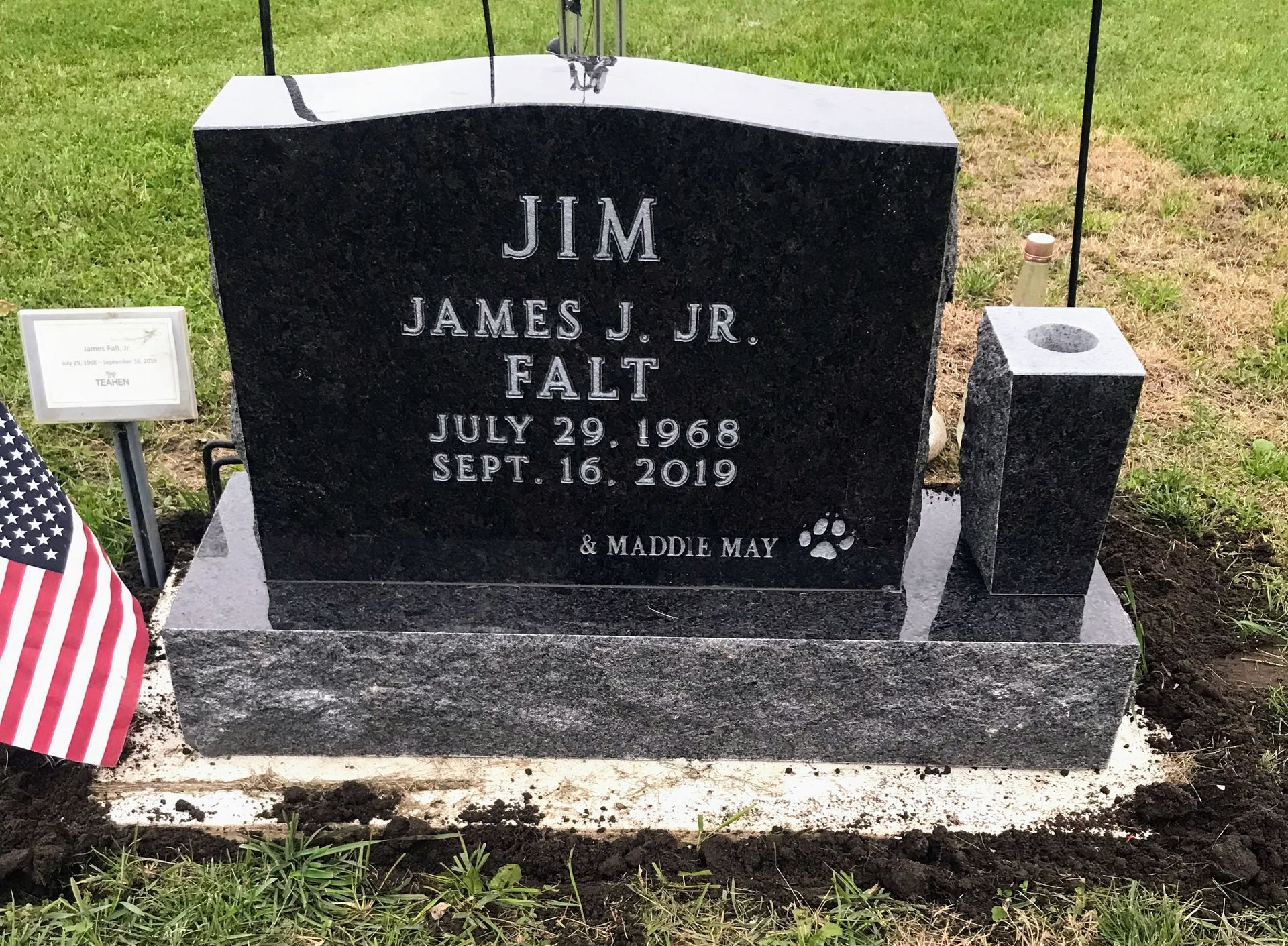 A black gravestone with the name Jim James Jr. written on it