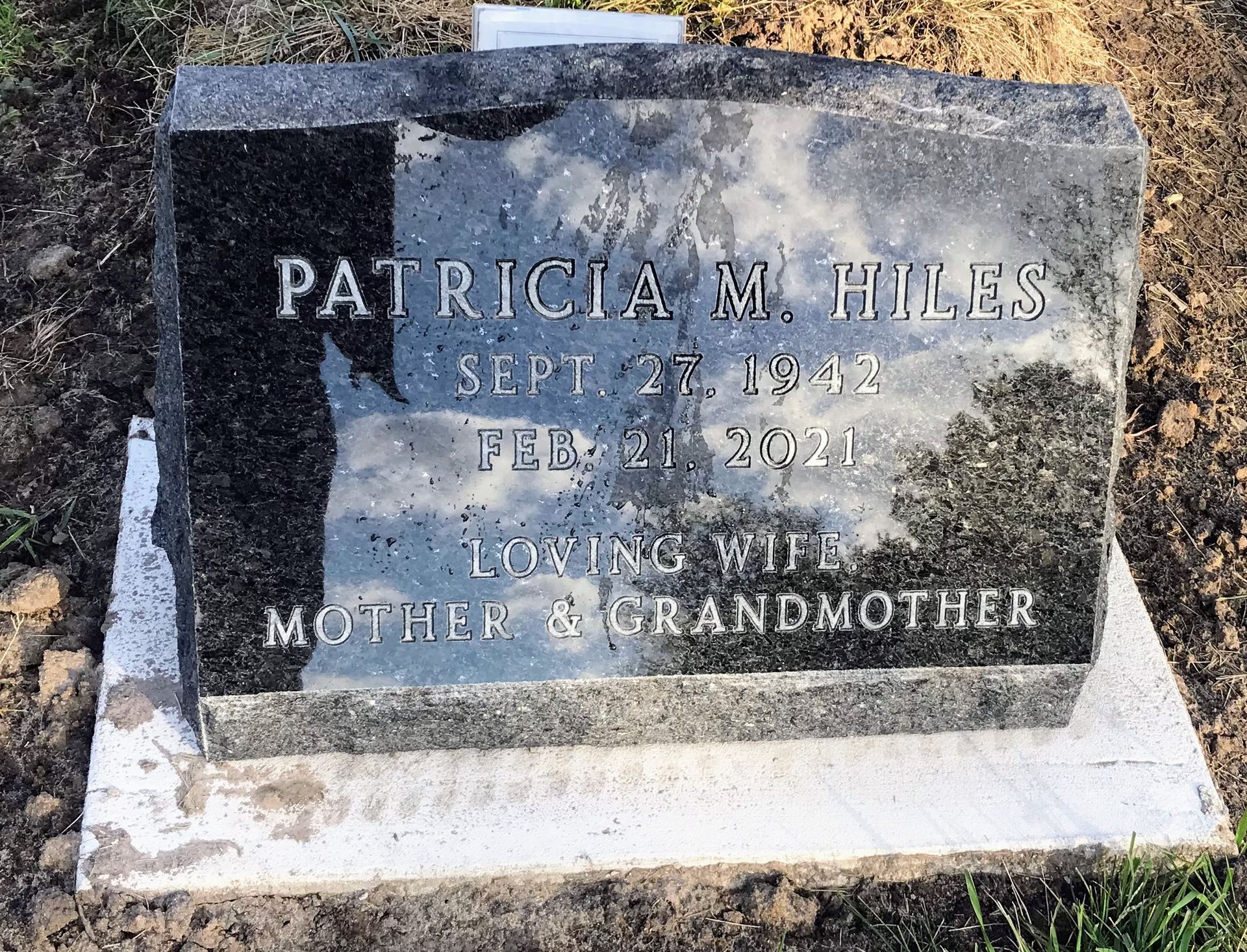 A gravestone for Patricia M. Hiles is sitting in the dirt